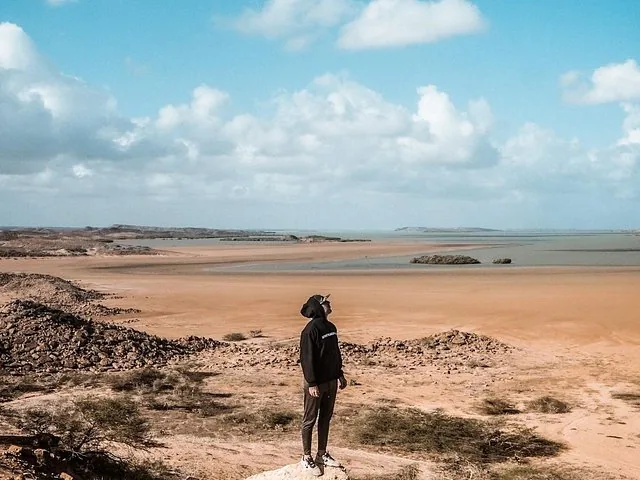 Una persona in piedi su una roccia ammira il paesaggio desertico della Guajira.
