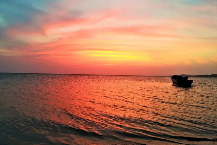 A beautiful sunset over the water with a small boat in La Guajira.