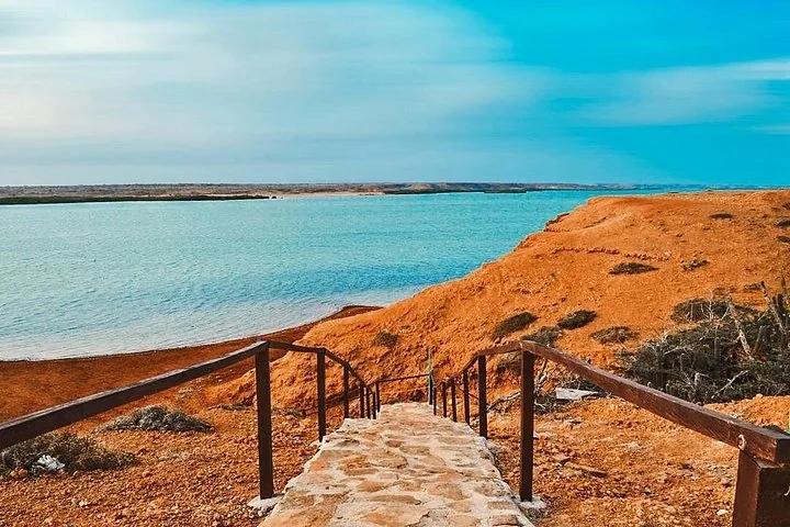 Steinstufen, die hinunter zum blauen Wasser führen, eingerahmt von roten Wüstenklippen.