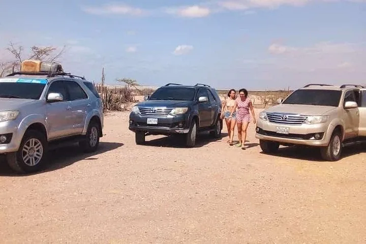 Veicoli fuoristrada parcheggiati nel deserto con una coppia che cammina verso di loro.